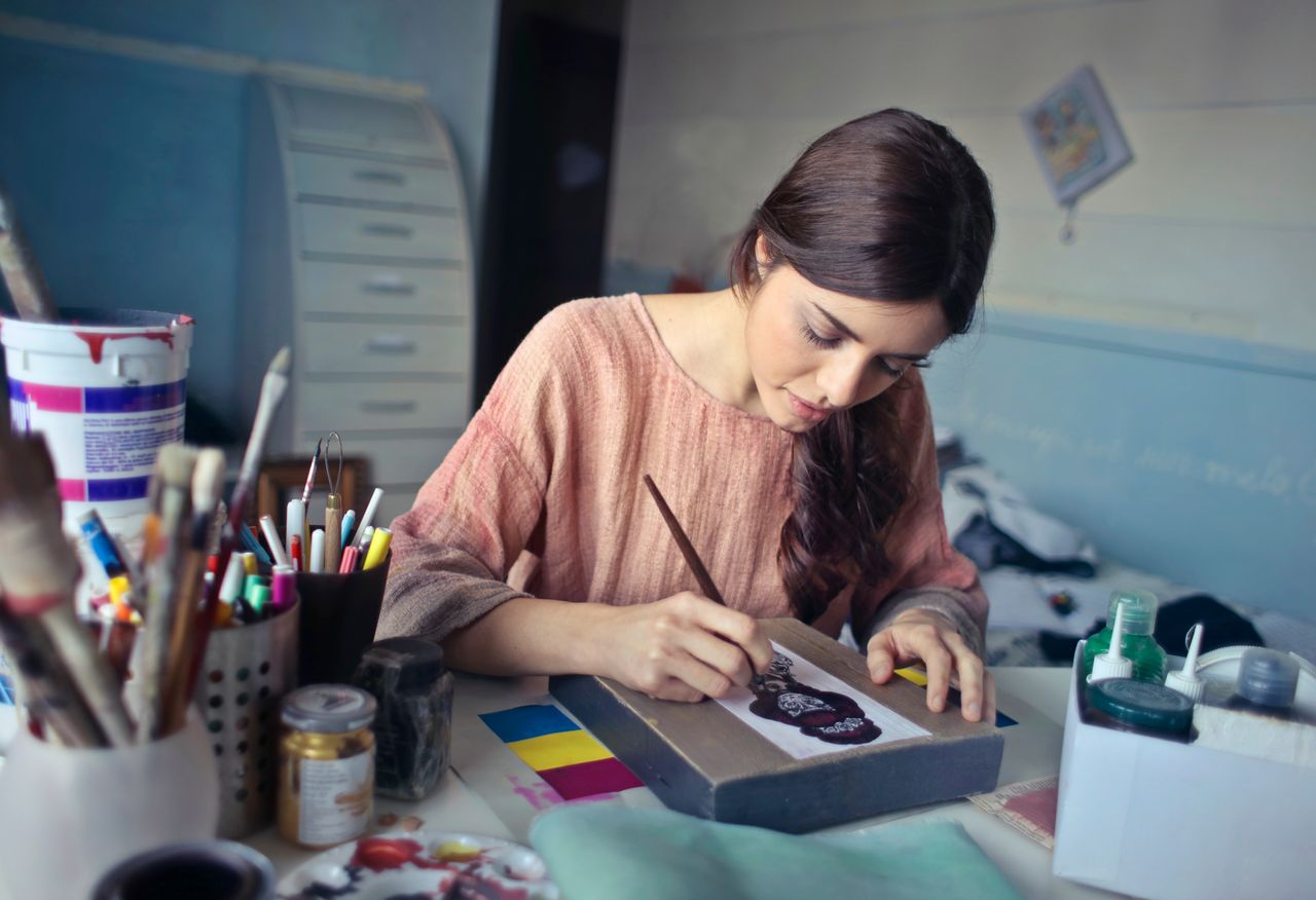 why-choose-me Female artist deeply engaged in painting at her creative studio workspace.